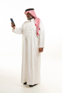 Saudi Man in Traditional Thobe Using Smartphone