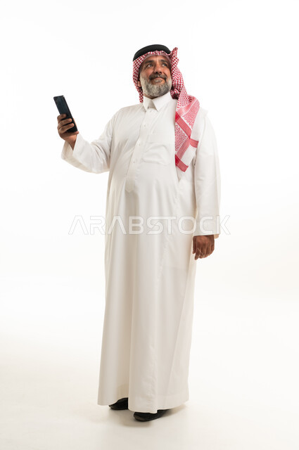 رجل سعودي مسن يحمل هاتف ذكي بخلفية بيضاء