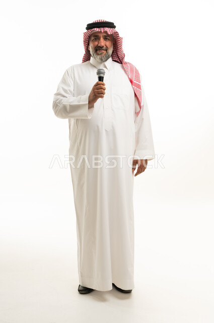 رجل سعودي بالثوب التقليدي يمسك بميكروفون في استوديو
