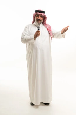 رجل سعودي بالزي التقليدي يمسك ميكروفون بخلفية بيضاء