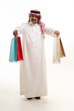 رجل سعودي يحمل أكياس تسوق على خلفية بيضاء