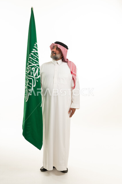 رجل سعودي مع العلم السعودي باللباس التقليدي