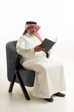 رجل سعودي بالزي التقليدي يقرأ كتاباً في الاستوديو