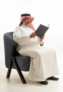 رجل سعودي بالزي التقليدي يقرأ كتاباً في الاستوديو