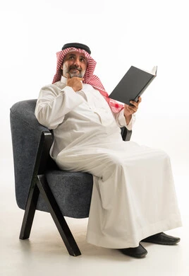 Saudi Man in Traditional Thobe Reading Book in Studio