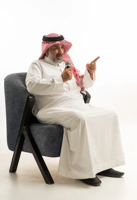 رجل سعودي بالزي التقليدي يتحدث عبر ميكروفون في استوديو