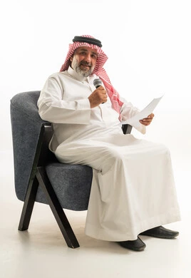 رجل سعودي بالزي التقليدي يمسك ميكروفون