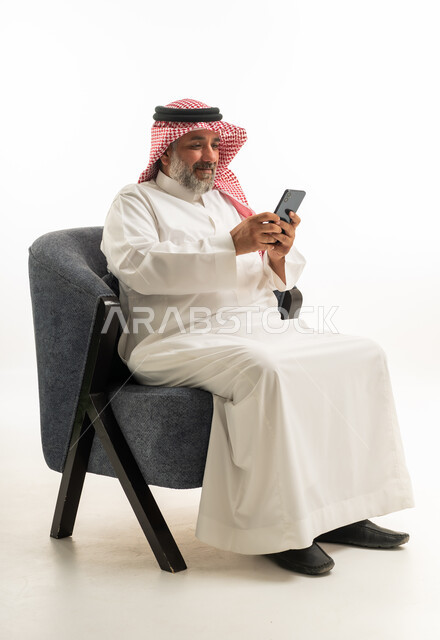 رجل سعودي بالثوب التقليدي يستخدم الهاتف الذكي