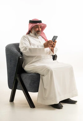 رجل سعودي بالثوب التقليدي يستخدم الهاتف الذكي