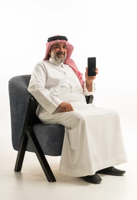 رجل سعودي بالزي التقليدي يحمل هاتف ذكي