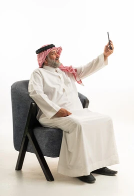 رجل سعودي بالثوب والزي التقليدي يلتقط صورة سيلفي