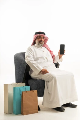 رجل سعودي مع هاتف ذكي وحقائب تسوق