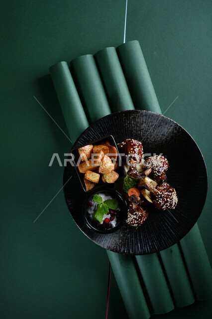 طبق من قطع الدجاج المقلي المقرمشة بالصوص والعسل ومكعبات البطاطا المقلية والسلطة الشهية مصورة على خلفية خضراء ، وجبات عربية ، وصفات وأطباق طعام لذيذة ، وجبات الطعام الشهية ، مطاعم عربية خليجية، كروما