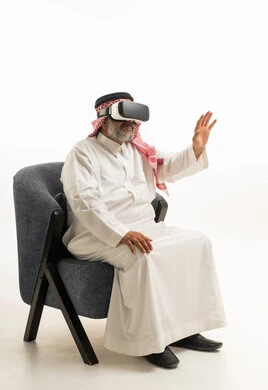 رجل سعودي يرتدي نظارة واقع افتراضي يجلس في استوديو