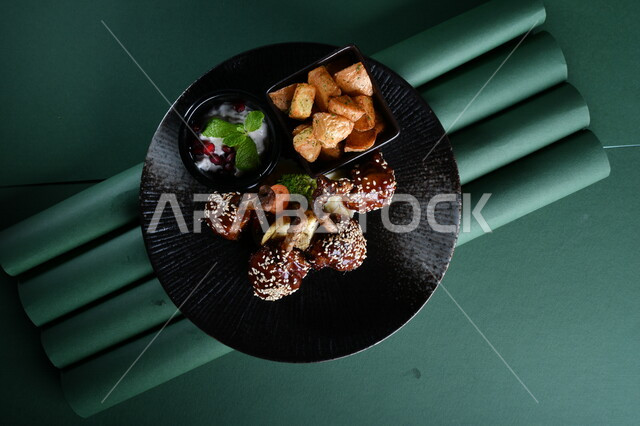 طبق من قطع الدجاج المقلي المقرمشة بالصوص والعسل ومكعبات البطاطا المقلية والسلطة الشهية مصورة على خلفية خضراء ، وجبات عربية ، وصفات وأطباق طعام لذيذة ، وجبات الطعام الشهية ، مطاعم عربية خليجية، كروما