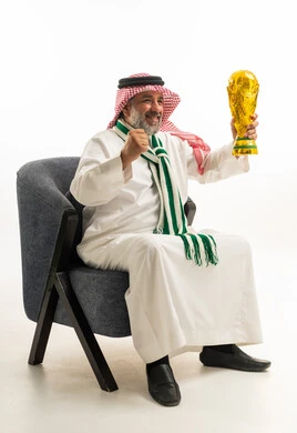 رجل سعودي بالزي التقليدي يحمل كأس كرة القدم الذهبي