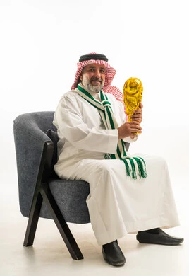 رجل سعودي بالزي التقليدي يحمل كأس العالم الذهبي
