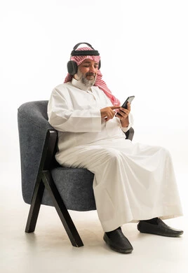 Saudi Man with Headphones and Smartphone in Armchair
