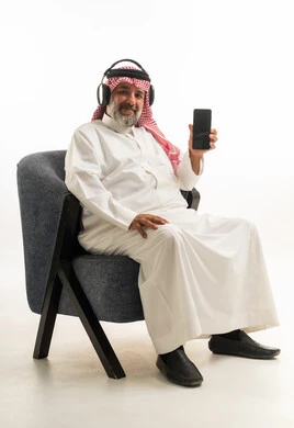 Saudi Man with Headphones Holding Smartphone in Studio