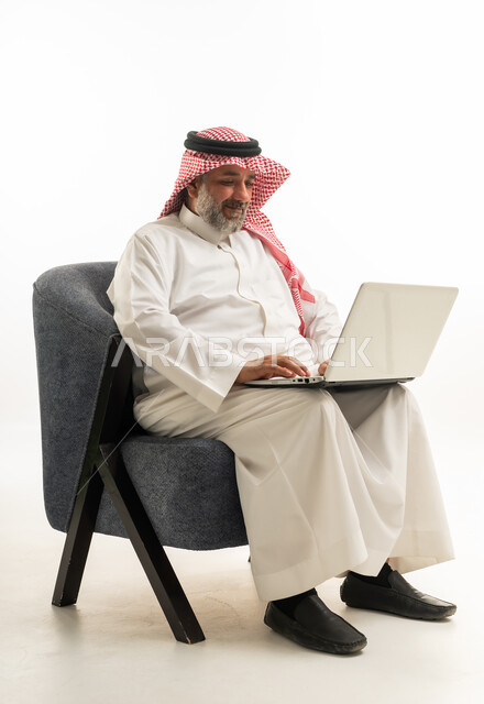 رجل سعودي بزي تقليدي يستخدم حاسوب محمول