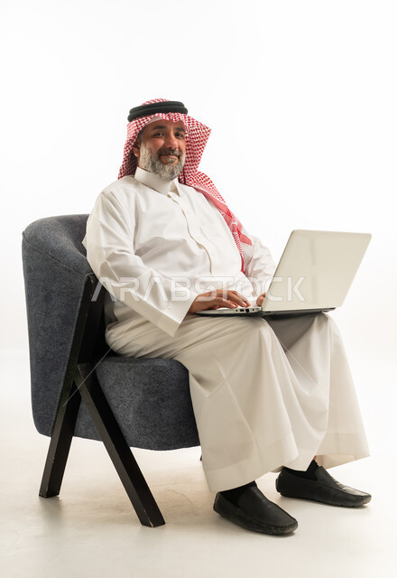 رجل سعودي يستخدم الكمبيوتر المحمول أمام خلفية بيضاء