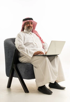 رجل سعودي يستخدم الكمبيوتر المحمول أمام خلفية بيضاء