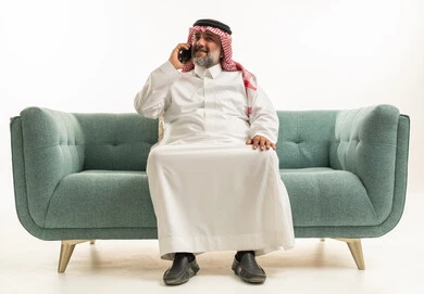 رجل سعودي على الأريكة يستخدم الهاتف الذكي في الاستوديو