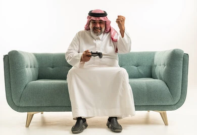 رجل سعودي يلعب ألعاب الفيديو ويحتفل على الأريكة