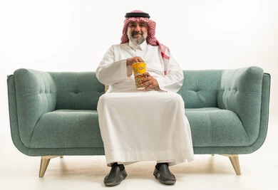 رجل سعودي يجلس على الأريكة يأكل الفشار في استوديو