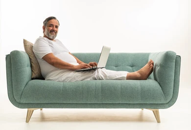 Saudi Man Using Laptop on Teal Sofa Studio Shot Background
