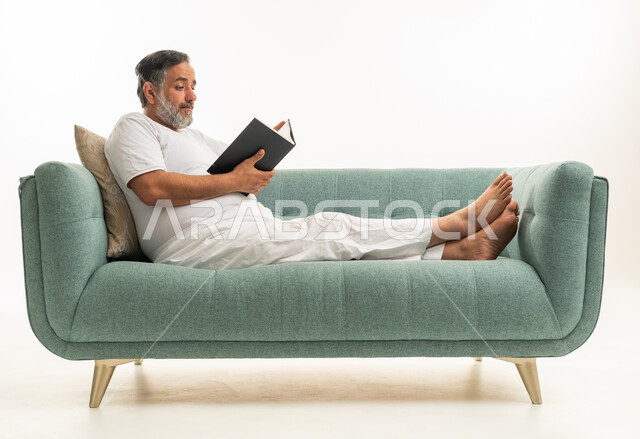 Saudi Man in White Clothes Reading on Sofa White Background