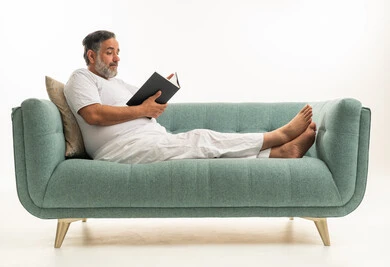 Saudi Man in White Clothes Reading on Sofa White Background