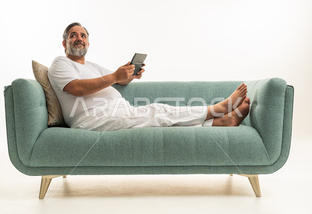 رجل عربي يسترخي على أريكة خضراء ويستخدم جهاز لوحي رقمي
