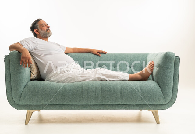 رجل خليجي في الخمسينات يسترخي على أريكة