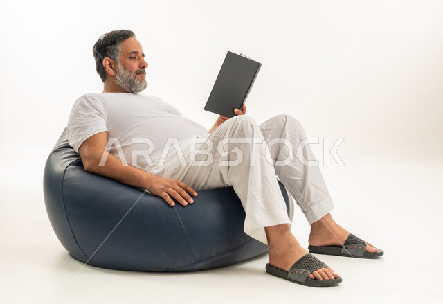 Middle-Aged Arab Man Reading Book on Blue Bean Bag