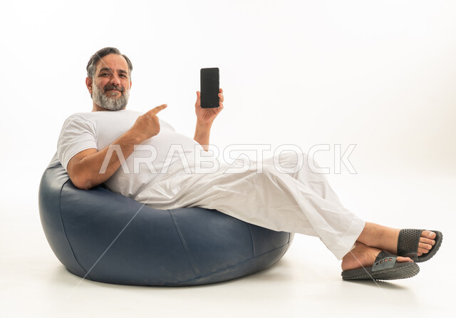 رجل سعودي مع هاتف ذكي على كرسي بين باج