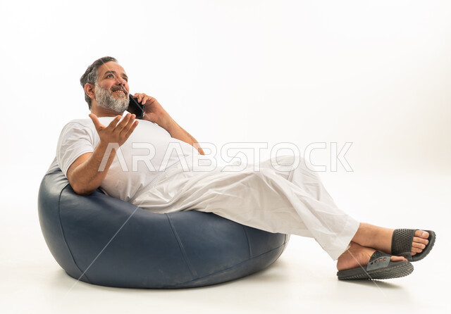 رجل سعودي يتحدث بالهاتف جالساً على مقعد محشو