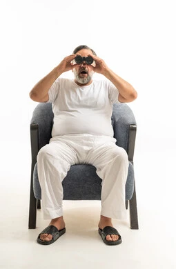رجل سعودي يحمل منظاراً جالساً على كرسي أزرق