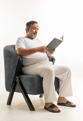 Saudi Man Reading Book in White Loungewear Armchair