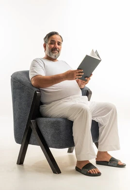 رجل عربي يقرأ كتاباً على كرسي مريح