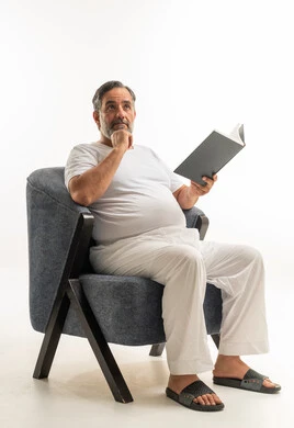 Middle-aged Saudi Man Reading a Book in Grey Armchair