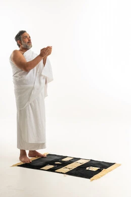 Saudi Man in Ihram Praying on Rug Studio Background
