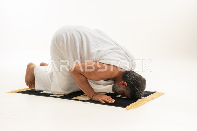 رجل عربي بملابس الإحرام يؤدي سجود الصلاة
