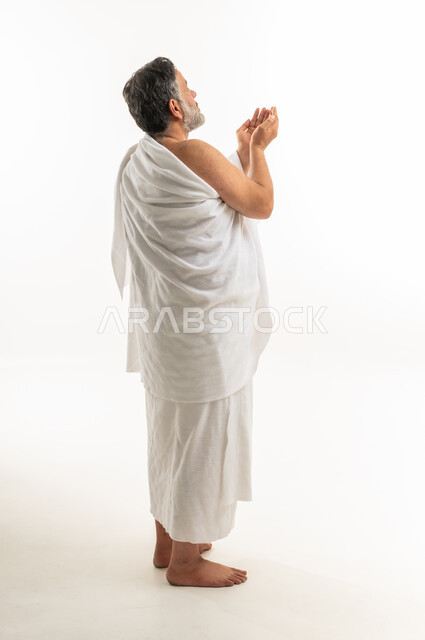رجل عربي بملابس الإحرام يدعو على خلفية بيضاء