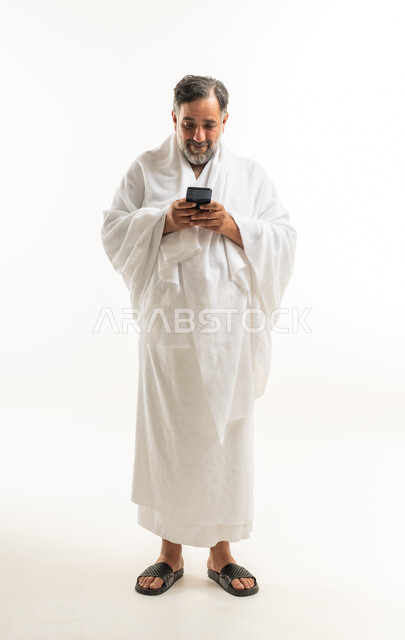 رجل مسلم بملابس الإحرام يستخدم الهاتف الذكي