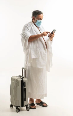 Saudi Pilgrim in Ihram Using Smartphone with Suitcase