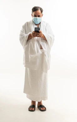 Saudi Pilgrim in Ihram with Mask and Smartphone