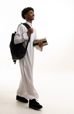 طالب سعودي بالثوب الأبيض يحمل كتباً وحقيبة