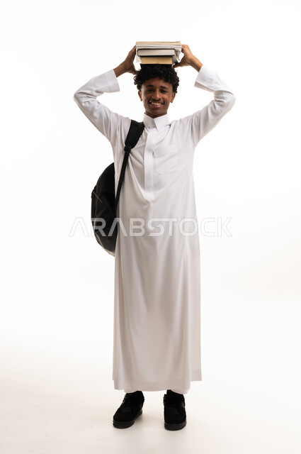طالب سعودي بالثوب التقليدي يحمل كتباً فوق رأسه