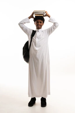 طالب سعودي بالثوب التقليدي يحمل كتباً فوق رأسه